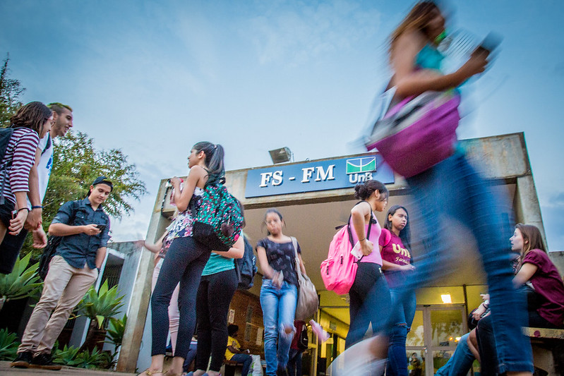 Estudantes conversando e caminhando na entrada do prédio da Faculdade de Saúde e da Faculdade de Medicina da UnB, ao entardecer